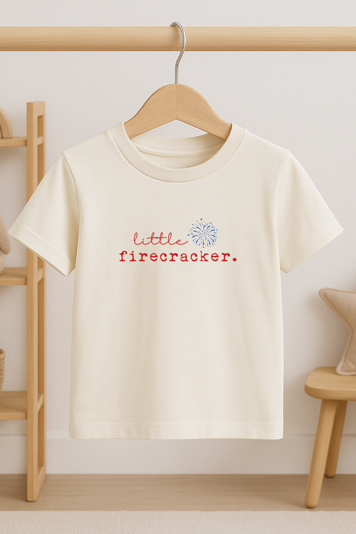 Kids organic off-white T-shirt on wooden hanger, red firecracker and blue burst graphic
