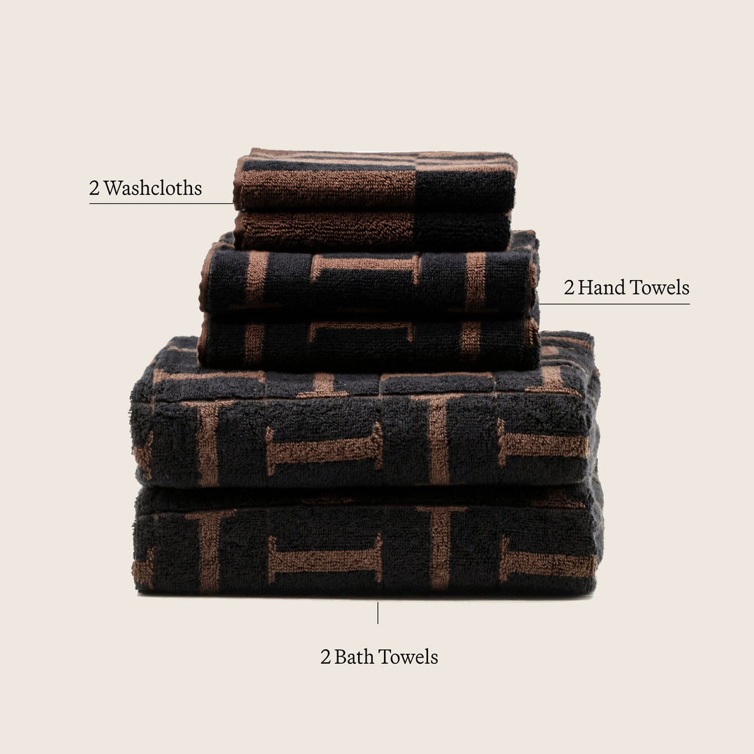 Stacked set of cotton towels: washcloths, hand towels, and bath towels in dark brown pattern