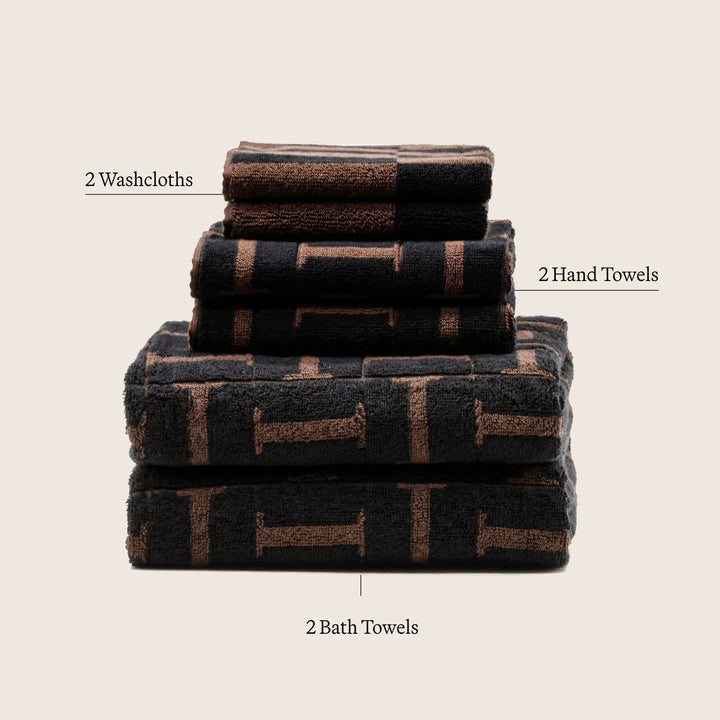 Stacked set of cotton towels: washcloths, hand towels, and bath towels in dark brown pattern