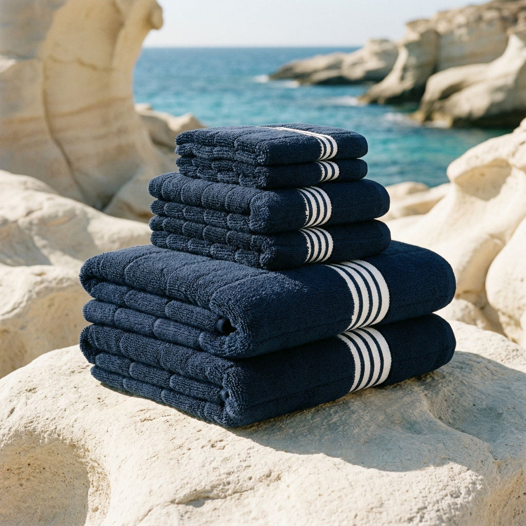 Navy cotton towels with white striped bands, stacked on a stone surface