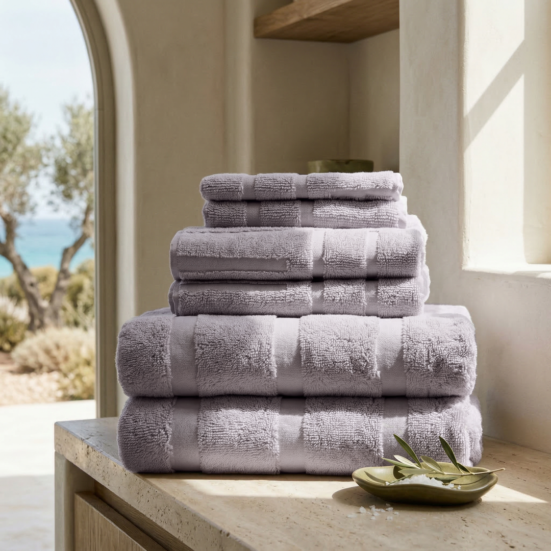 Stack of lavender cotton towels with striped bands and terry texture
