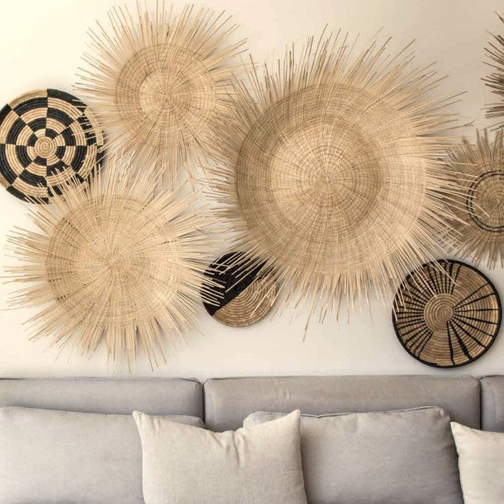 Woven sunburst wall plates in natural raffia with one dark spiral accent