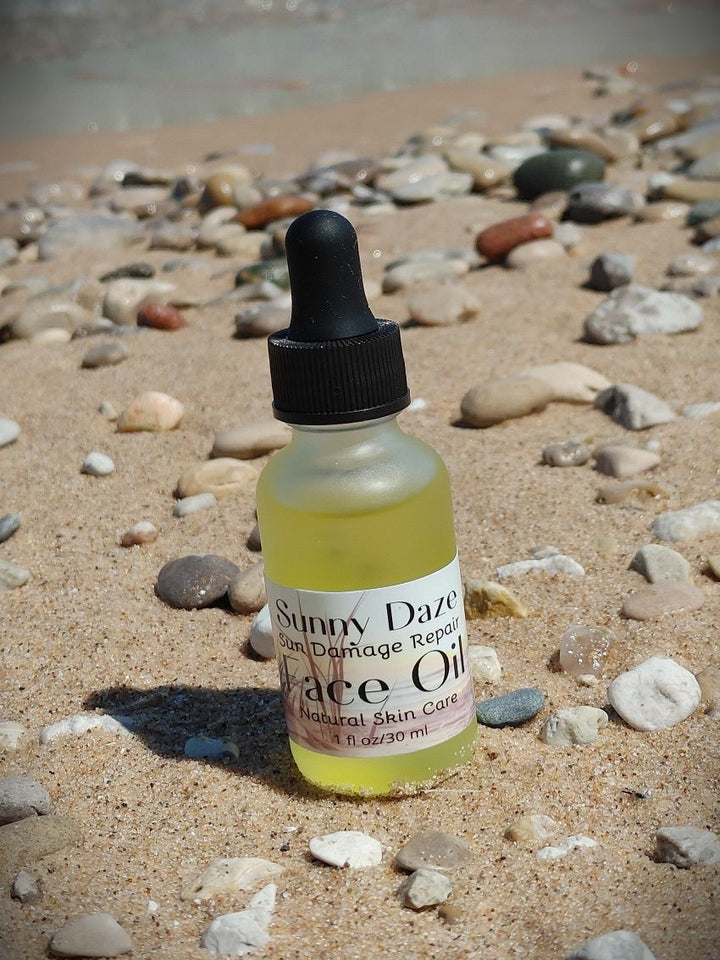 Yellow face oil bottle with black dropper on sand, Face Oil label visible