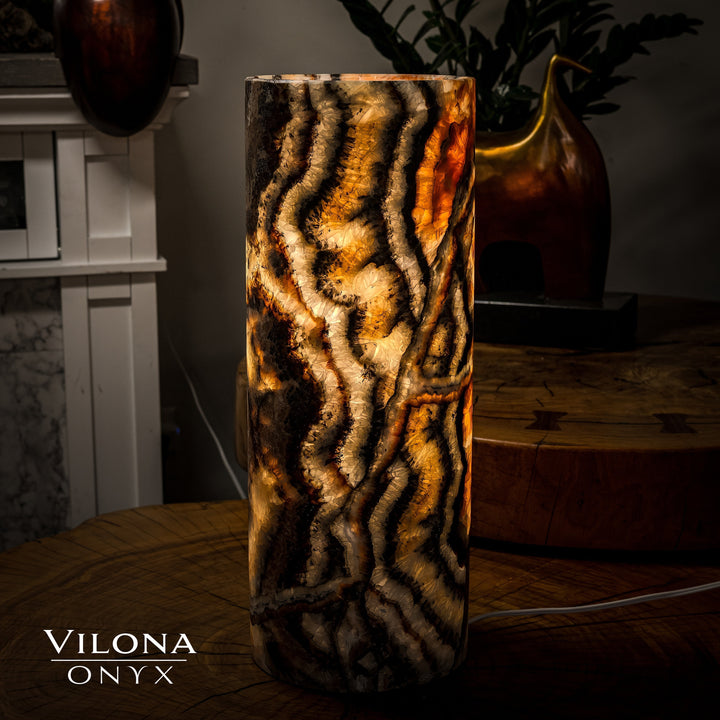 Dark onyx table lamp cylinder with bright amber glow through textured swirling stone