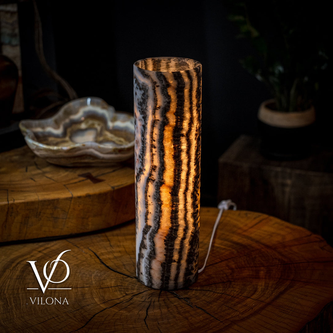Onyx table lamp with warm amber glow, striped crystal column with dark bands