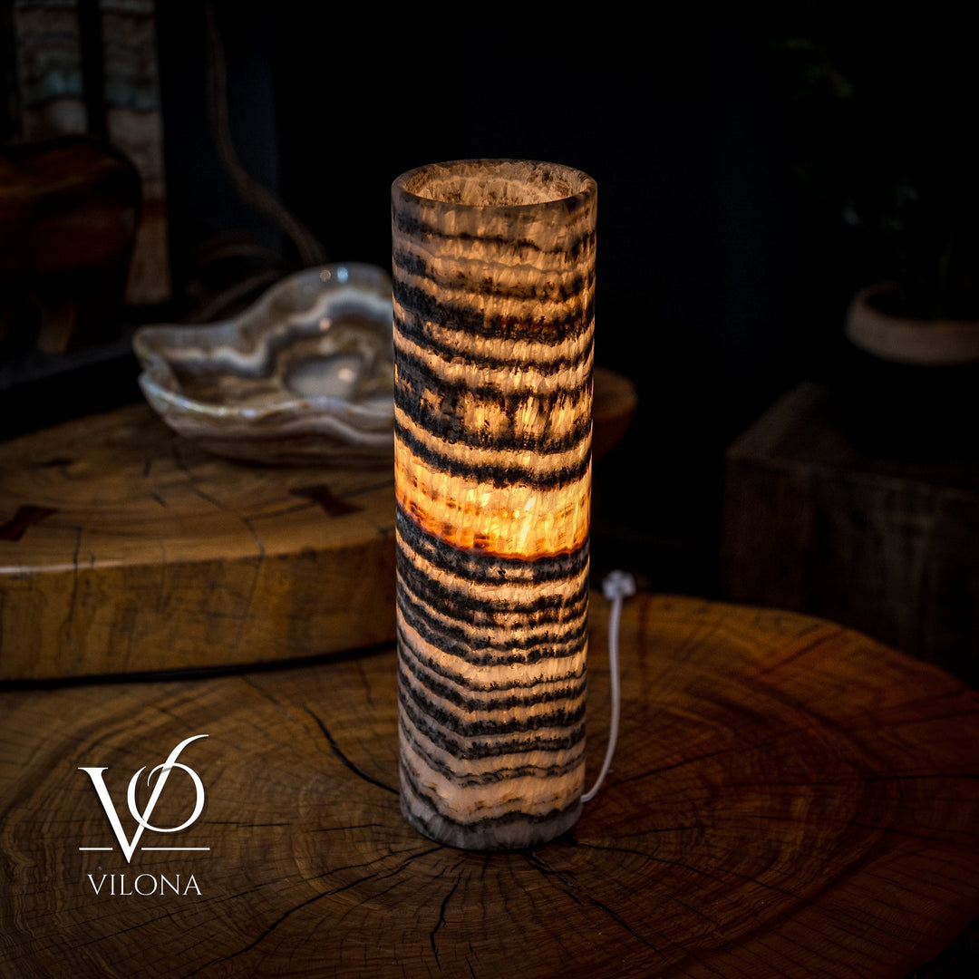Cylindrical onyx crystal table lamp with amber-lit interior and dark concentric striping