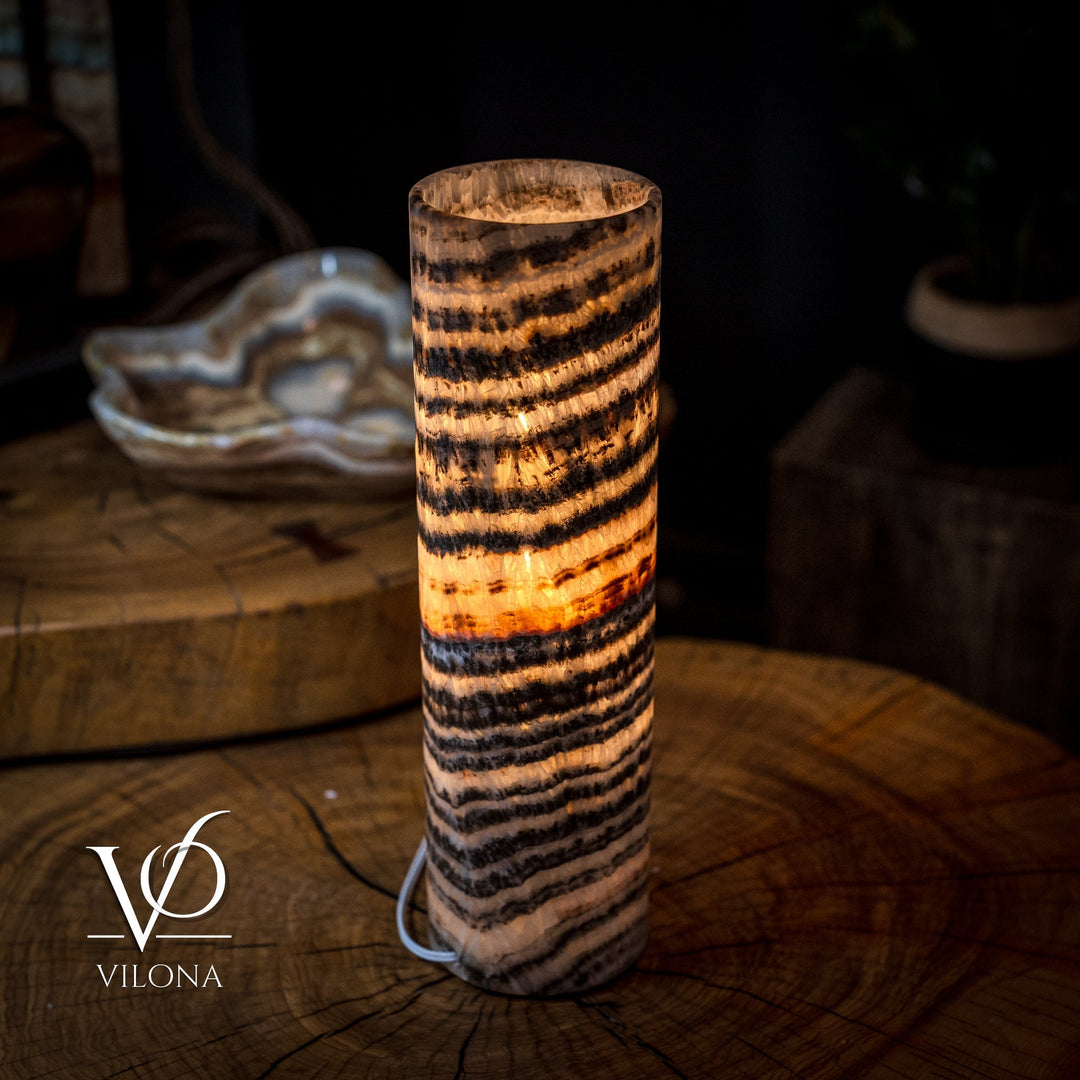 Cylindrical onyx crystal lamp with warm amber glow and black-and-tan striped pattern