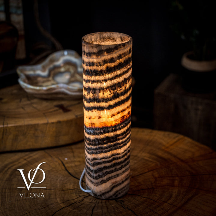 Cylindrical onyx crystal lamp with warm amber glow and black-and-tan striped pattern