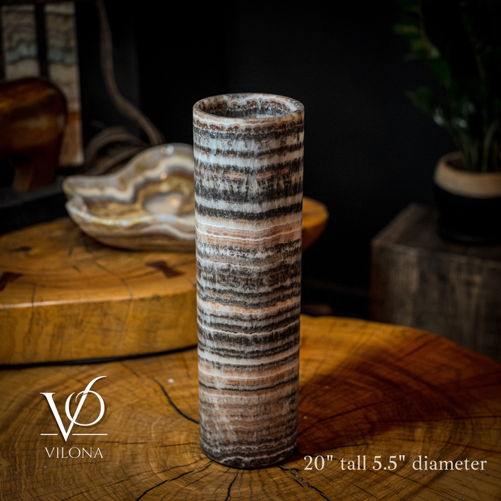 Tall cylindrical table lamp with gray and black striped stone body and warm top glow