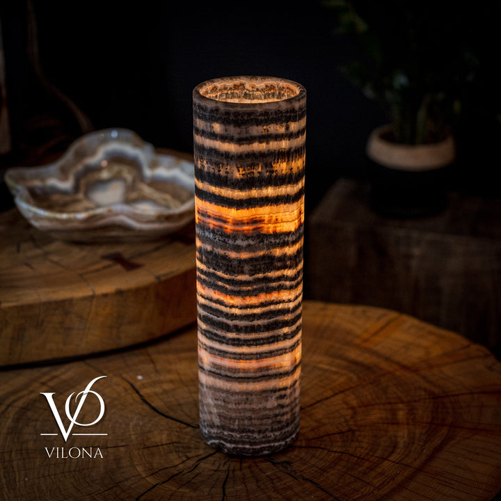 Cylindrical table lamp with amber glow through textured striped onyx-style surface