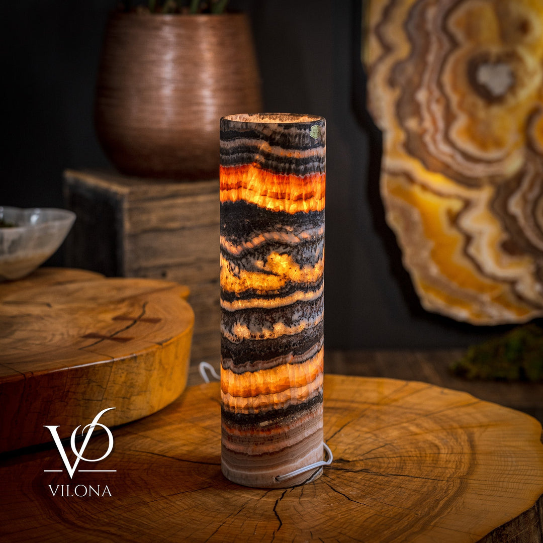 Cylindrical onyx crystal table lamp with warm orange glow through striped body.
