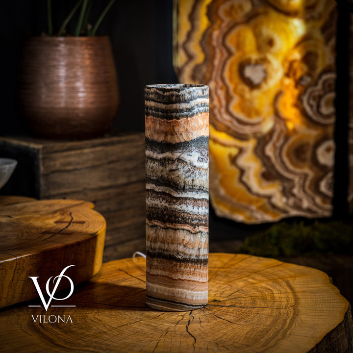 Cylindrical onyx crystal table lamp, striped glass body glowing warm orange.