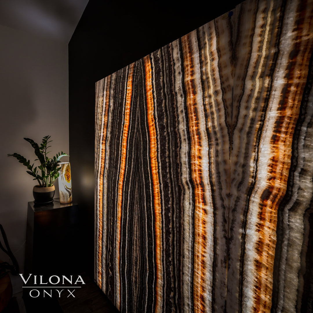 Close-up onyx wall panel with vertical orange amber lines over dark and cream streaks