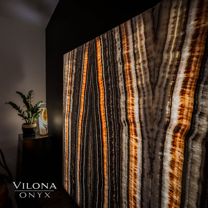 Close-up onyx wall panel with vertical orange amber lines over dark and cream streaks