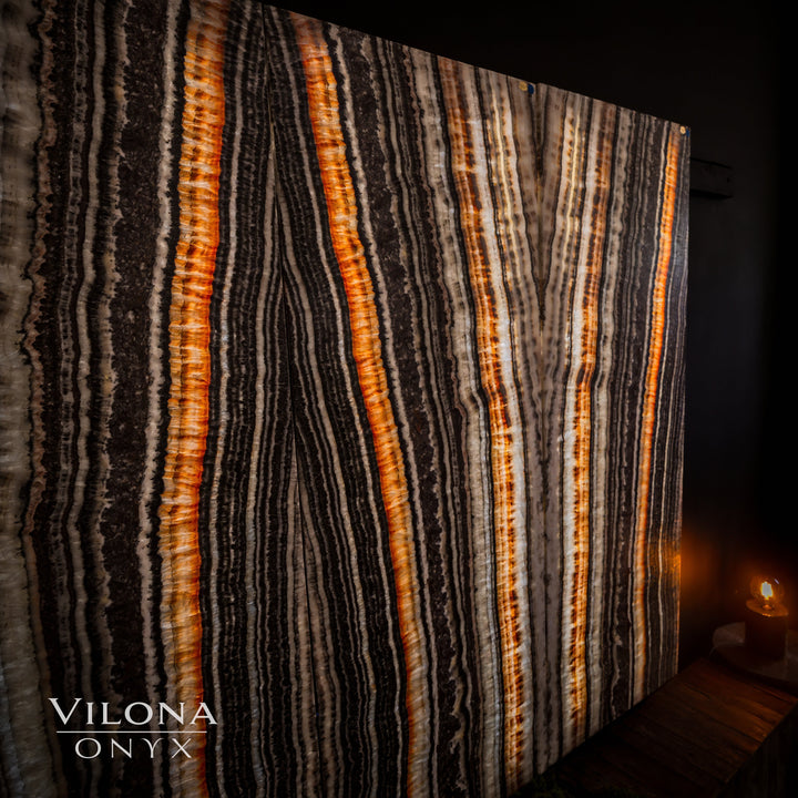 Striped onyx wall panel with tall vertical amber, cream, and charcoal lines