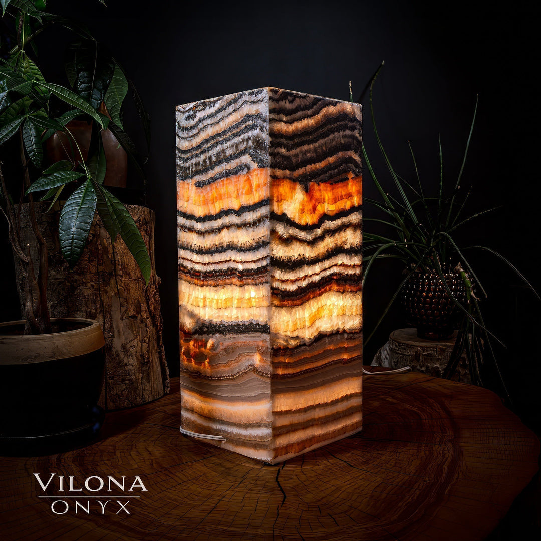 Medium square table lamp, close front view of striped onyx with warm orange illumination