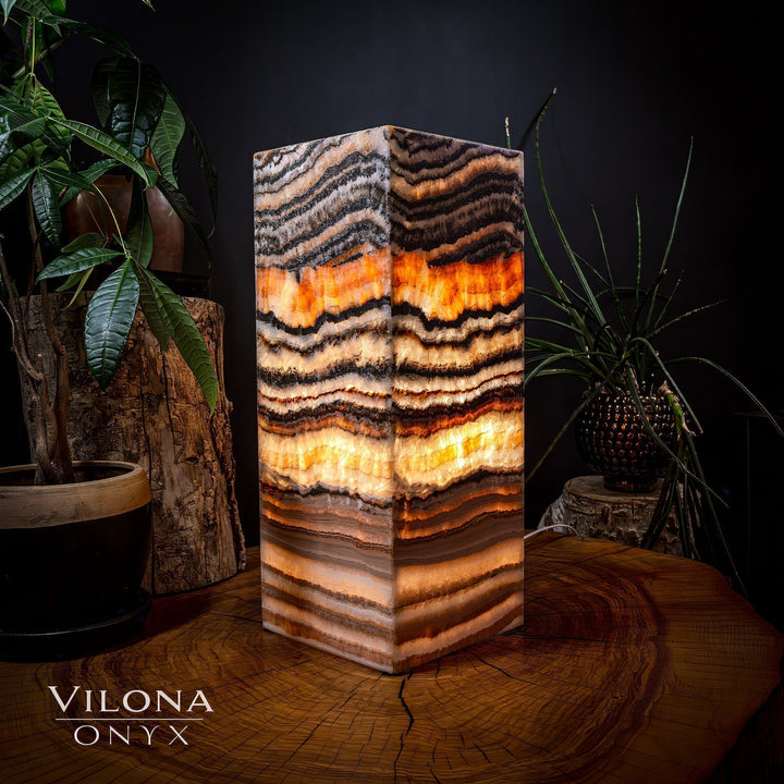 Medium square table lamp with geometric striped onyx shade and warm amber light