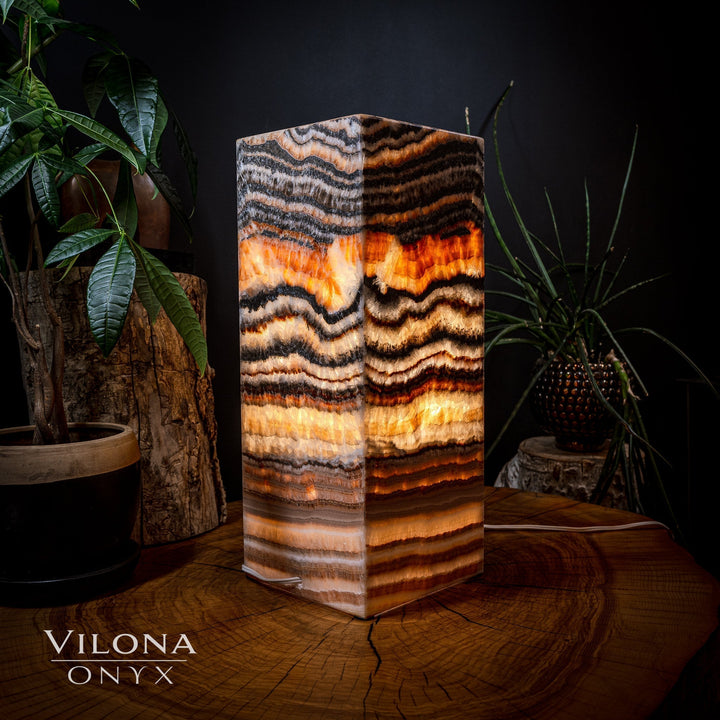 Square onyx table lamp with glowing amber centers and black-and-cream wavy bands