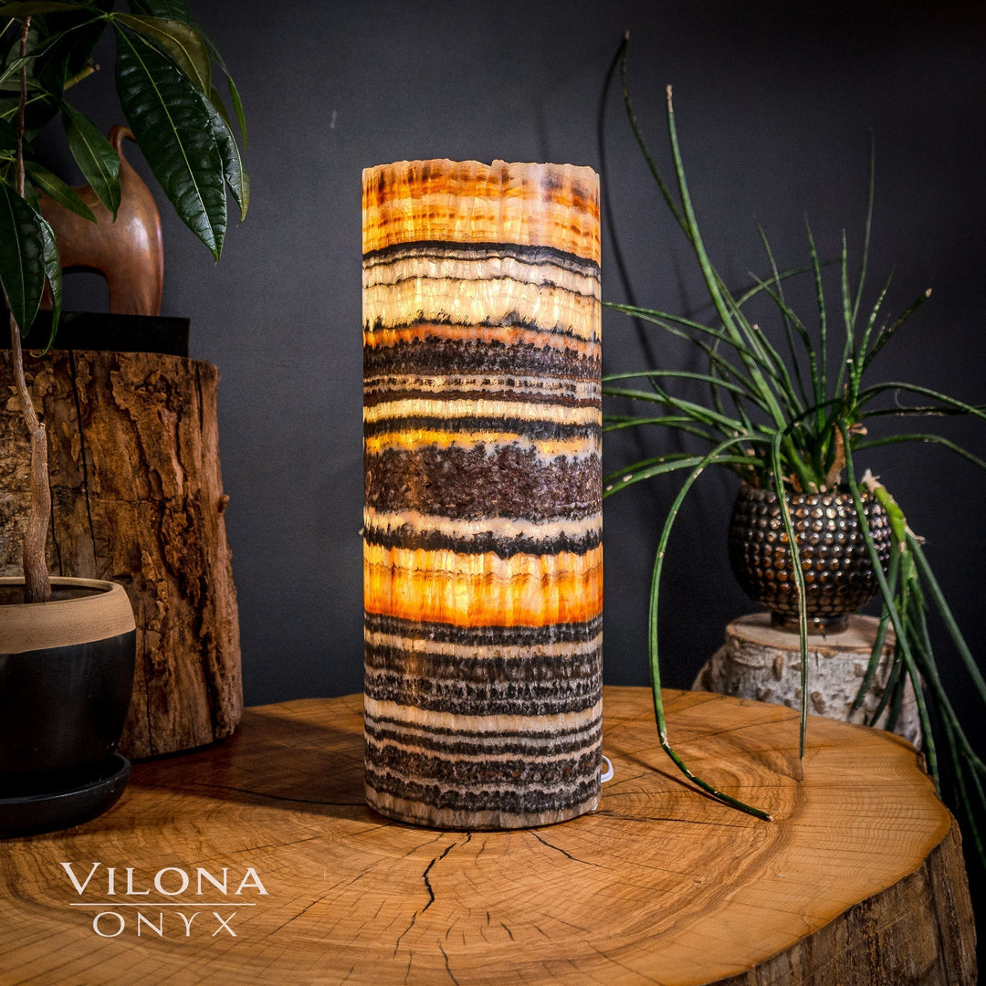 Cylindrical onyx table lamp with orange, cream, and dark banded stripes on the shade.