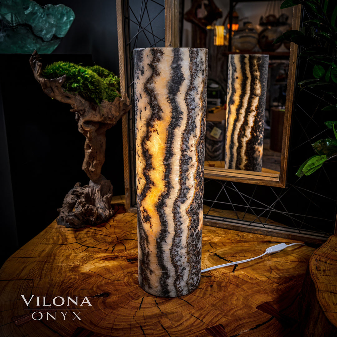 Onyx table lamp with tall cylindrical stone body, dramatic striped marbling and warm light glow