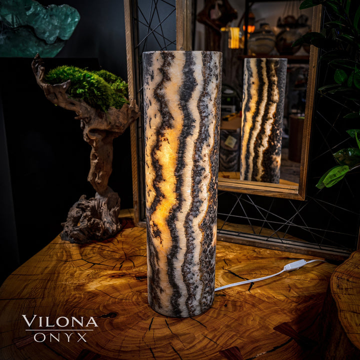 Onyx table lamp with tall cylindrical stone body, dramatic striped marbling and warm light glow