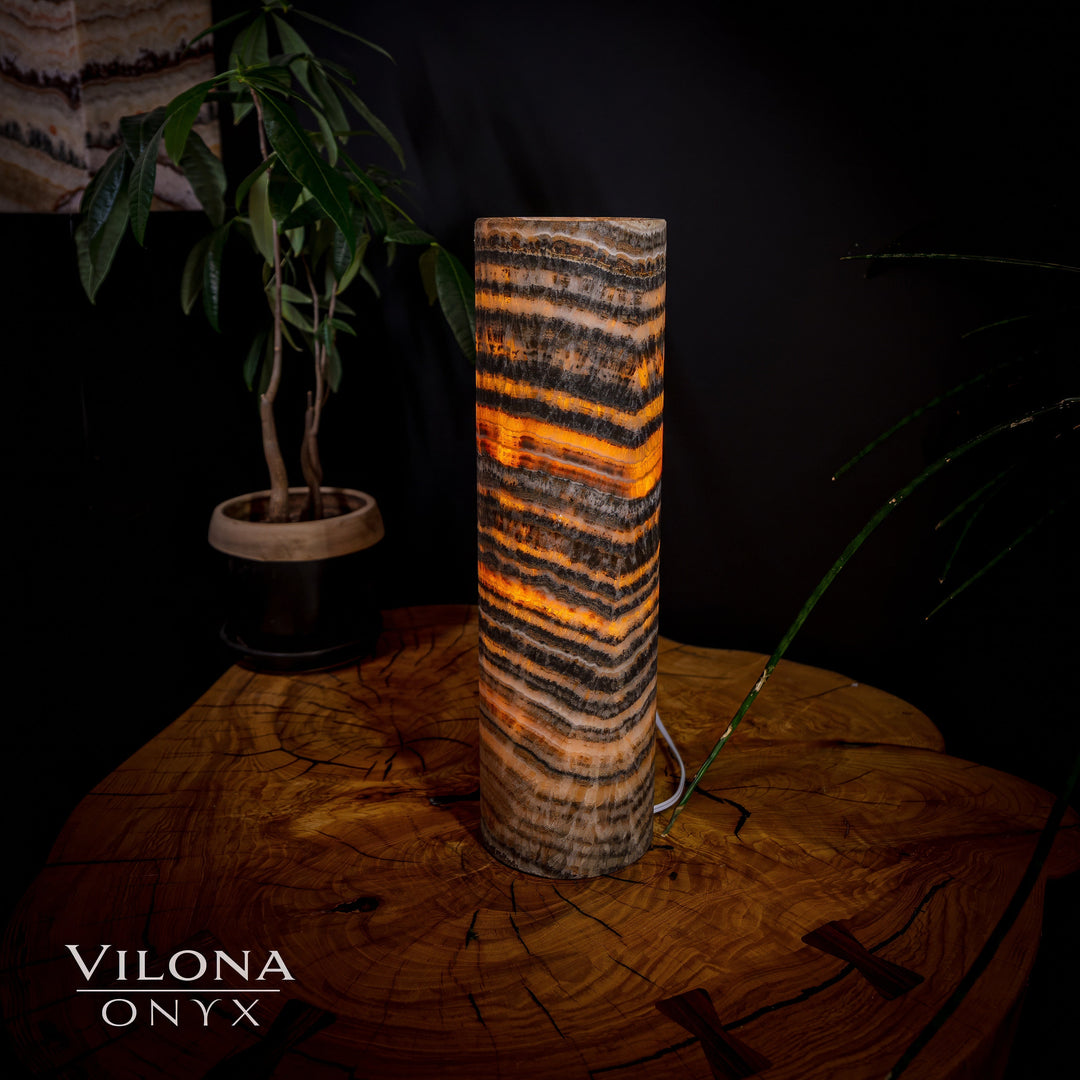 Table lamp with cylindrical onyx shade featuring dark and orange banded stripes