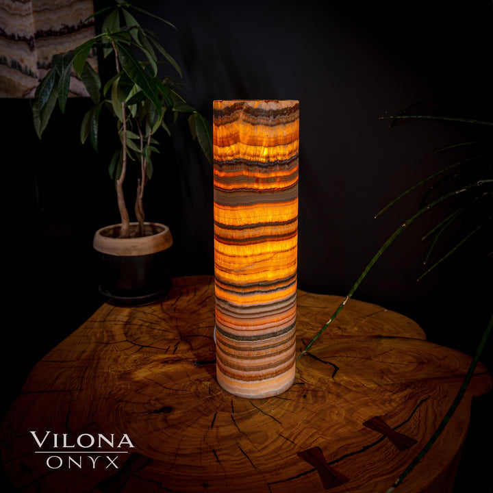 Cylindrical onyx table lamp with warm amber and dark banded stone shade