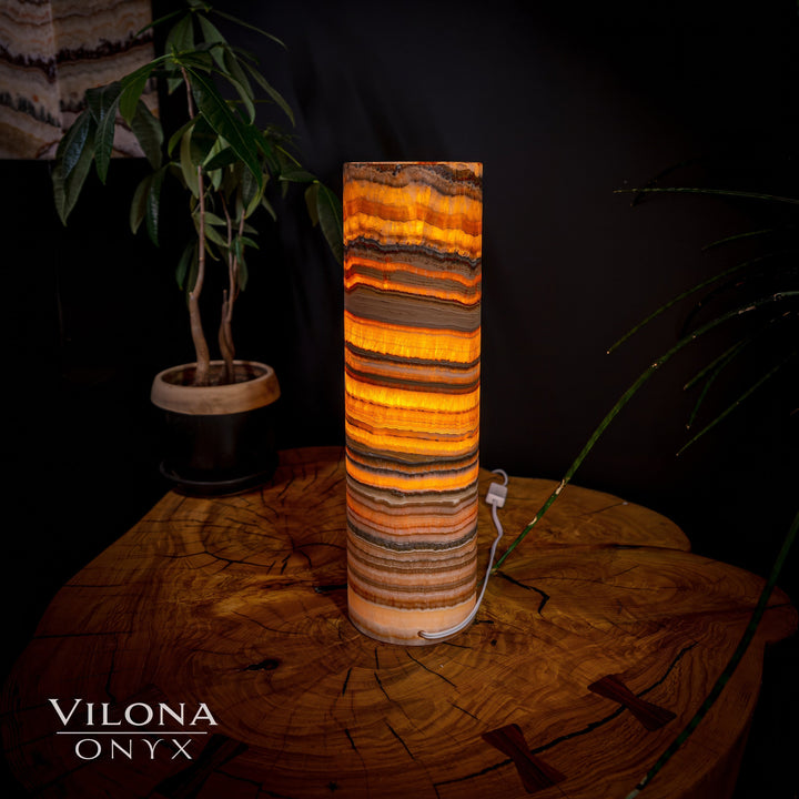 Cylindrical onyx table lamp with rich amber orange and dark horizontal stone stripes