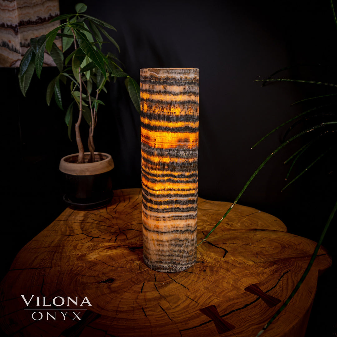 Cylindrical onyx table lamp with amber, black, and cream wavy stripes.