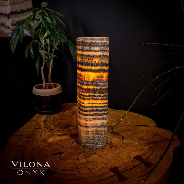 Cylindrical onyx table lamp with amber, black, and cream wavy stripes.