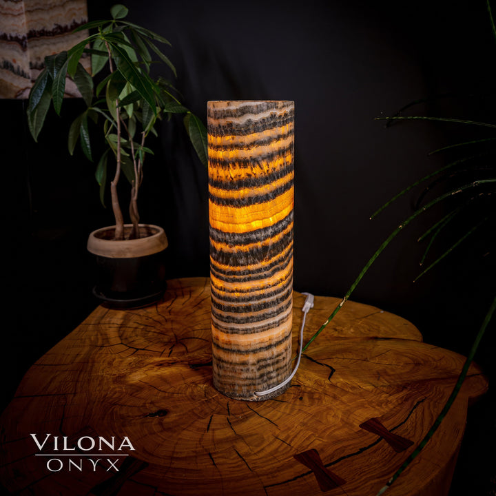 Cylindrical onyx table lamp with amber banded stripes and a dark base.