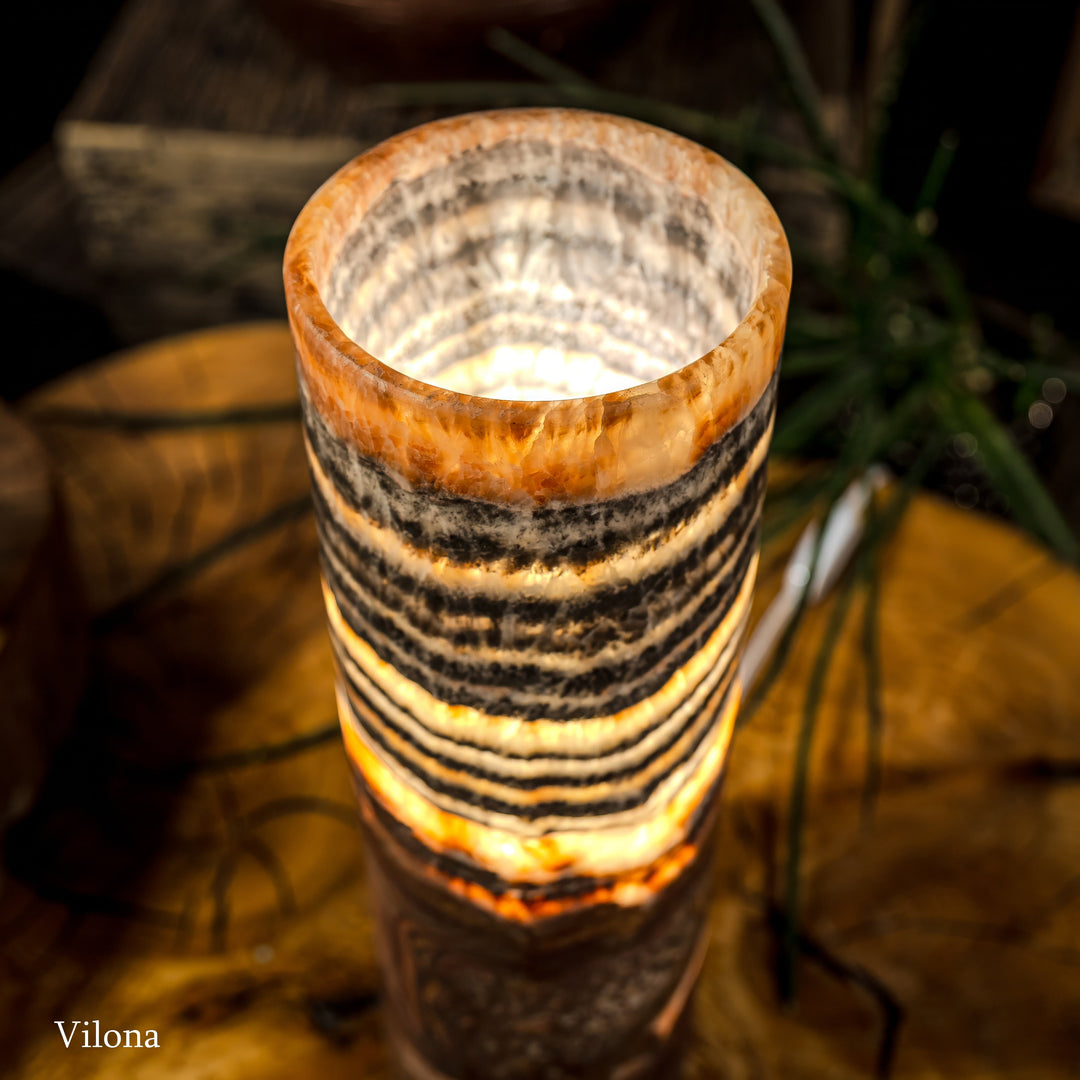 Close-up of cylindrical lamp top with amber glow and black-and-cream banded pattern