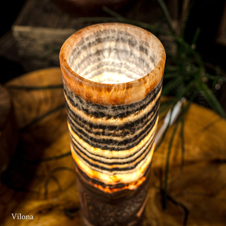 Close-up of cylindrical lamp top with amber glow and black-and-cream banded pattern