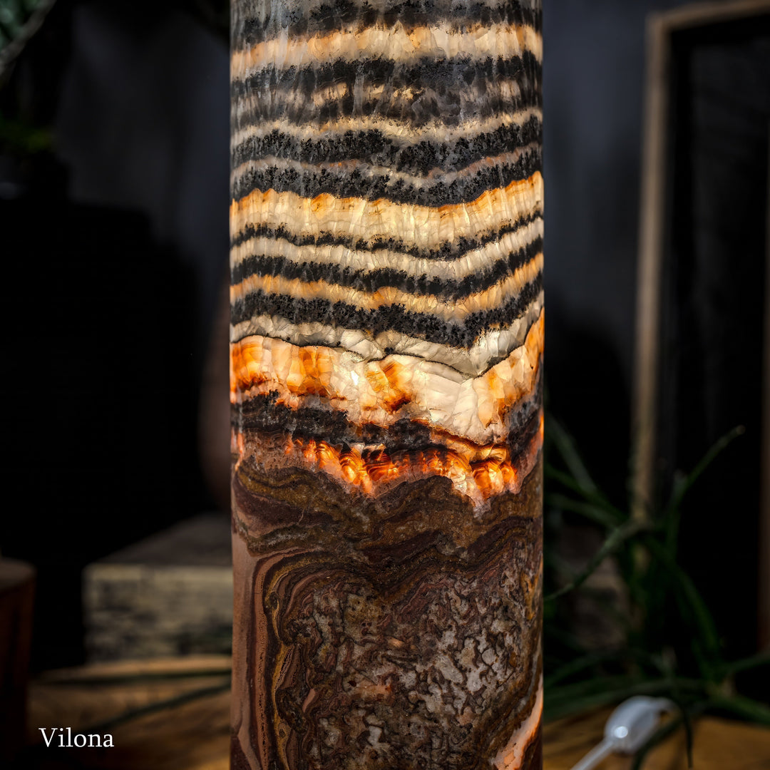Close-up of cylindrical lamp body with black-and-cream stripes and warm orange sections