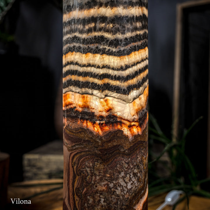 Close-up of cylindrical lamp body with black-and-cream stripes and warm orange sections