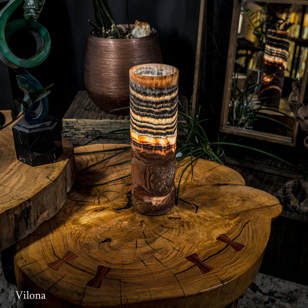 Cylindrical table lamp with black-and-cream wavy bands and warm amber glow on top