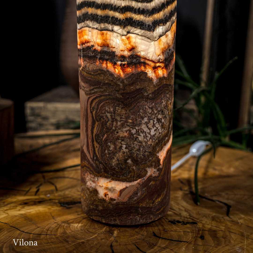 Lower close-up of cylindrical lamp with dark textured pattern and glowing amber interior