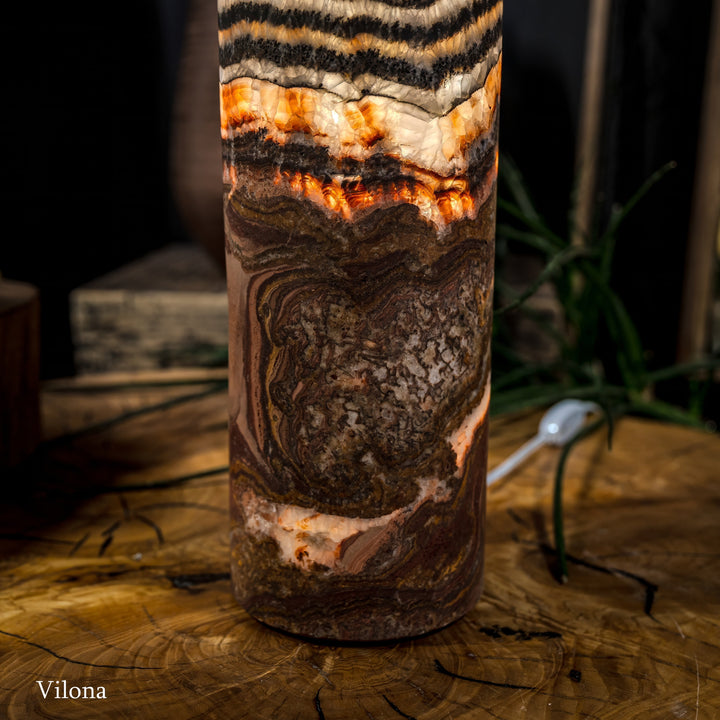 Lower close-up of cylindrical lamp with dark textured pattern and glowing amber interior