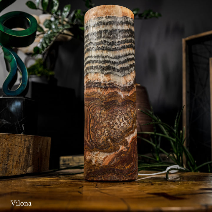 Full view cylindrical table lamp with black-and-cream stripes and warm amber glow