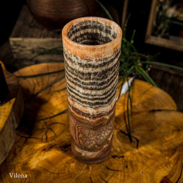 Cylindrical table lamp with black wavy bands, cream tones, and warm lit top opening