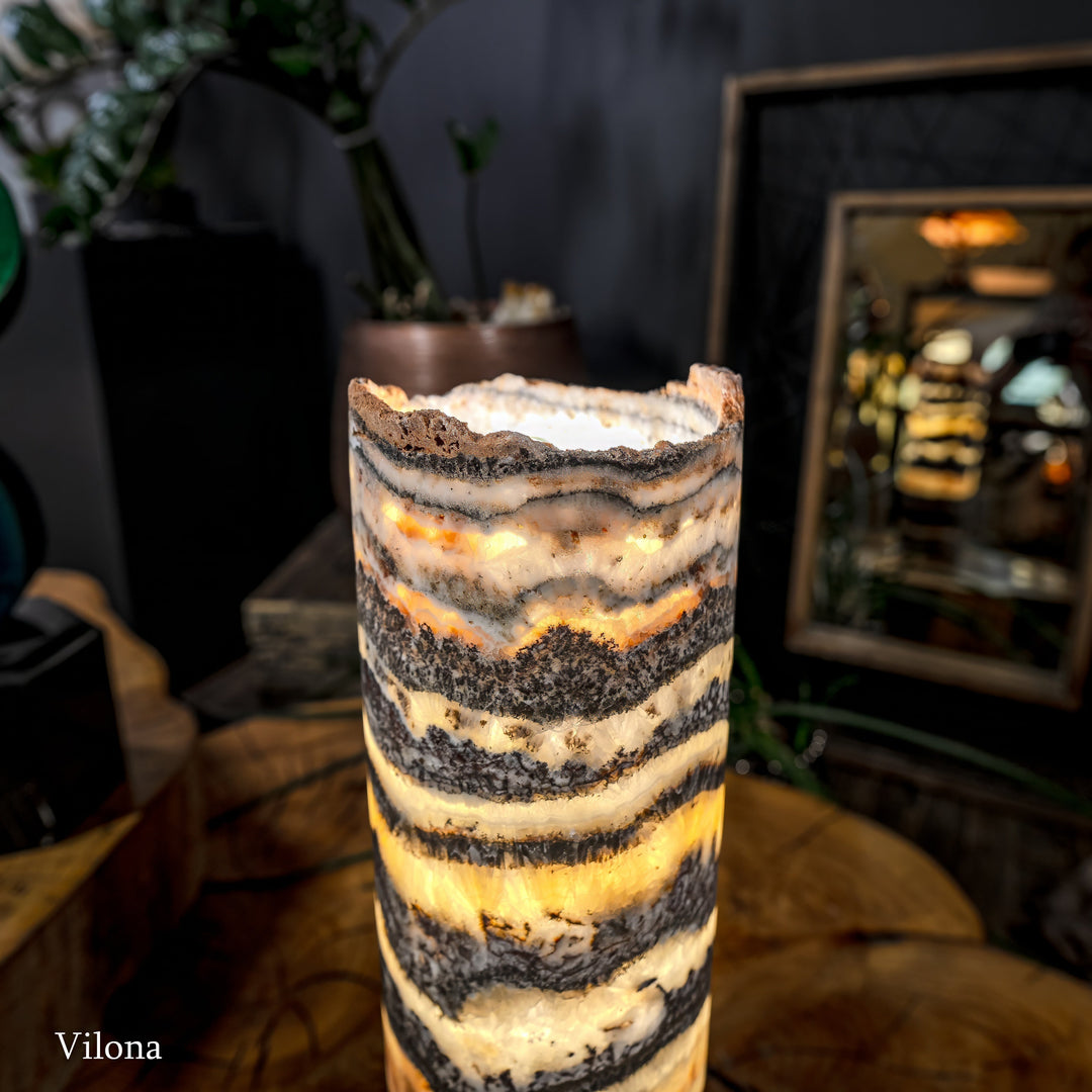 Cylindrical onyx-pattern table lamp, warm light through striped stone shade