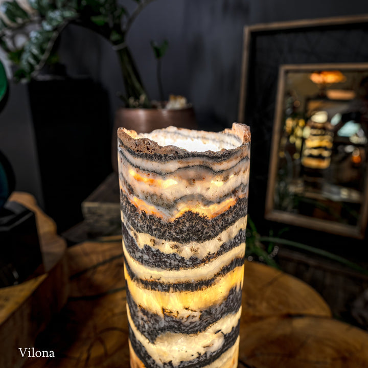 Cylindrical onyx-pattern table lamp, warm light through striped stone shade