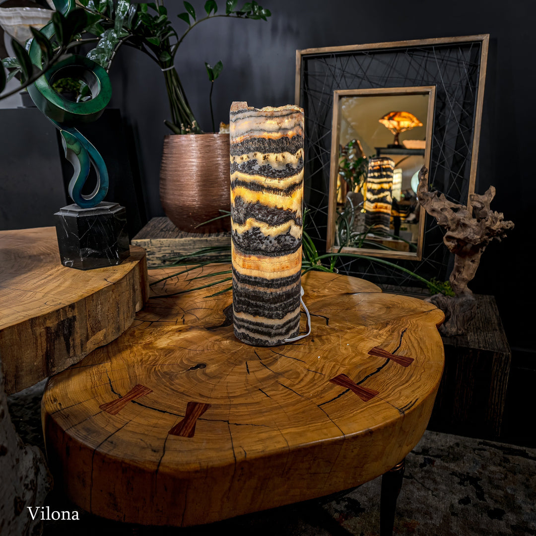 Tall cylindrical onyx-pattern table lamp with warm light through striped shade