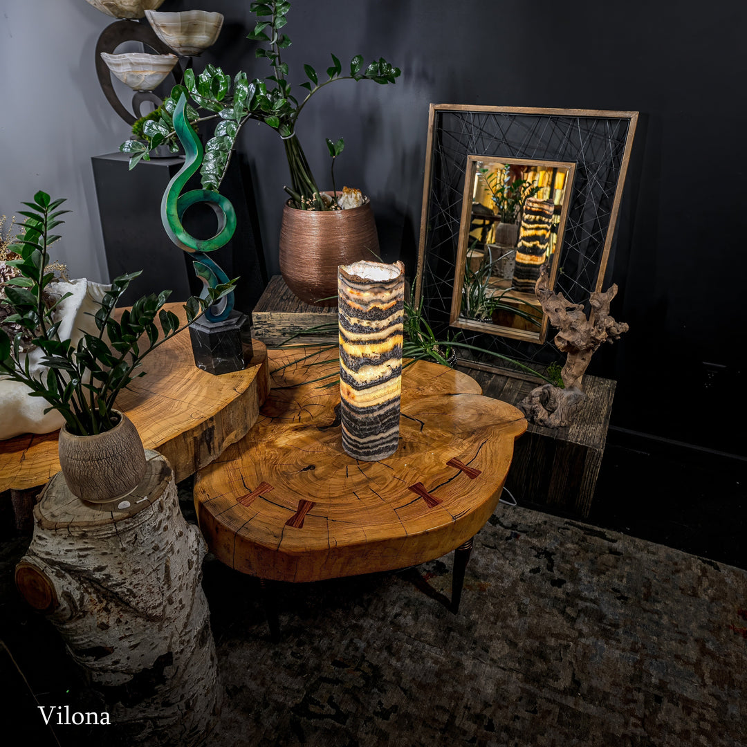 Table lamp with cylindrical patterned shade on round wooden side table