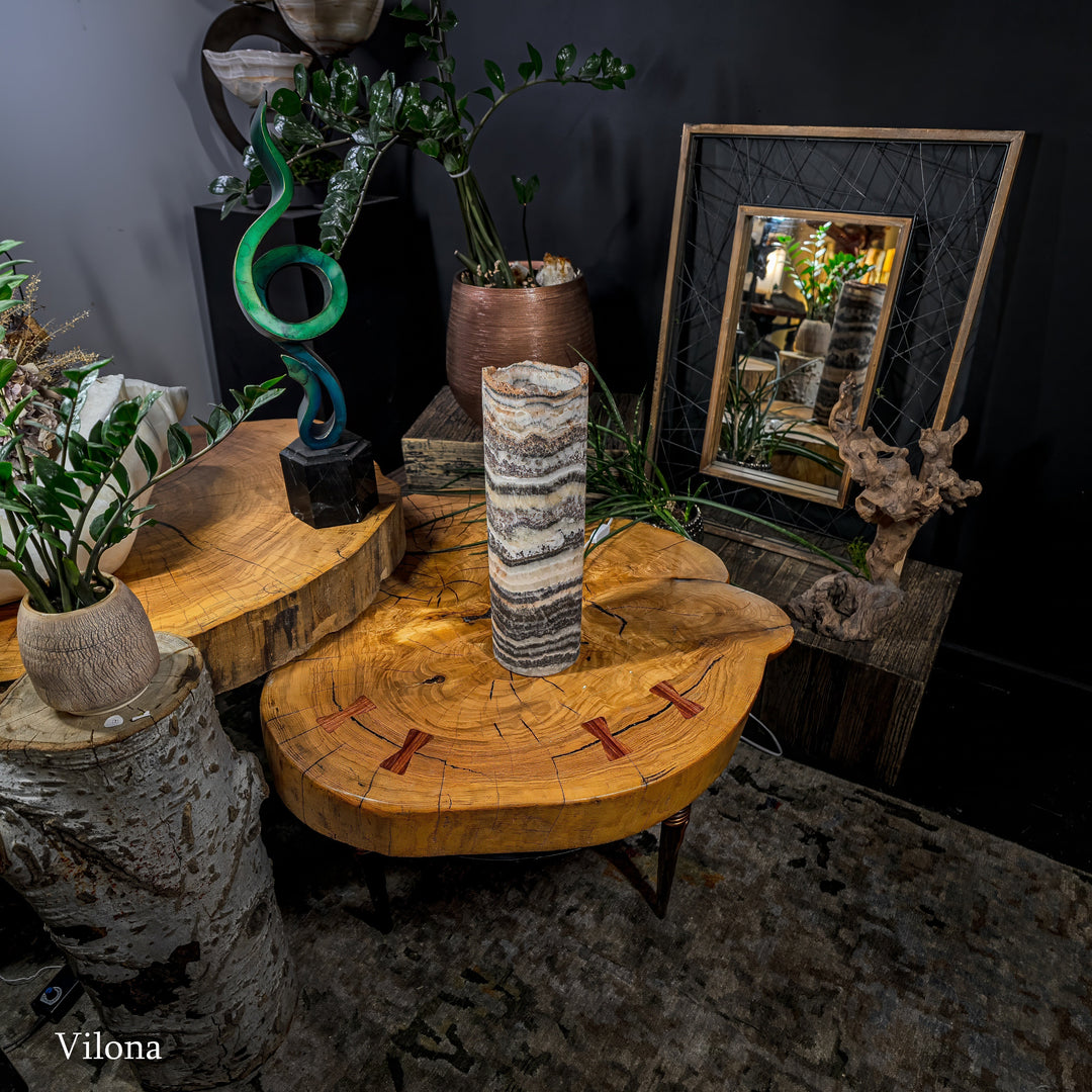 Table lamp with cylindrical patterned shade on round wooden end table