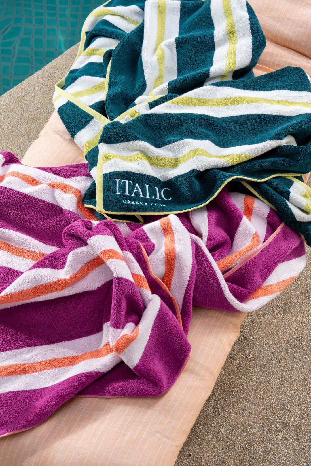 Cotton beach towel close-up in purple with orange-and-white striped bands and “ITALIC” text.