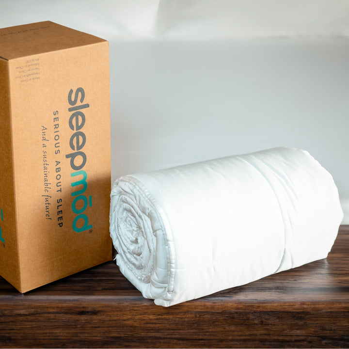 White rolled cooling comforter beside Sleepmoof shipping box