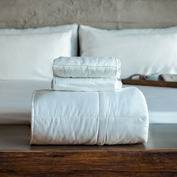 Light blue folded comforter with matching pillow shams set on bed frame