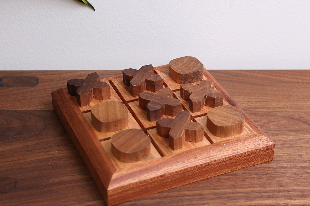 Handmade wooden tic-tac-toe game board with carved wooden pieces in a 3x3 grid