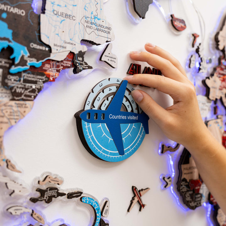 Wooden world map travel tracker with blue compass; hands holding the piece